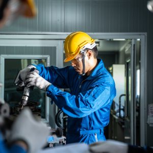 Asian mechanical workers working on milling machine.